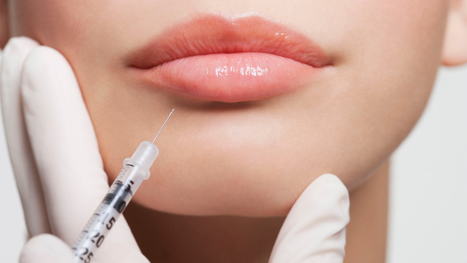 Close up of woman receiving botox injection in lips