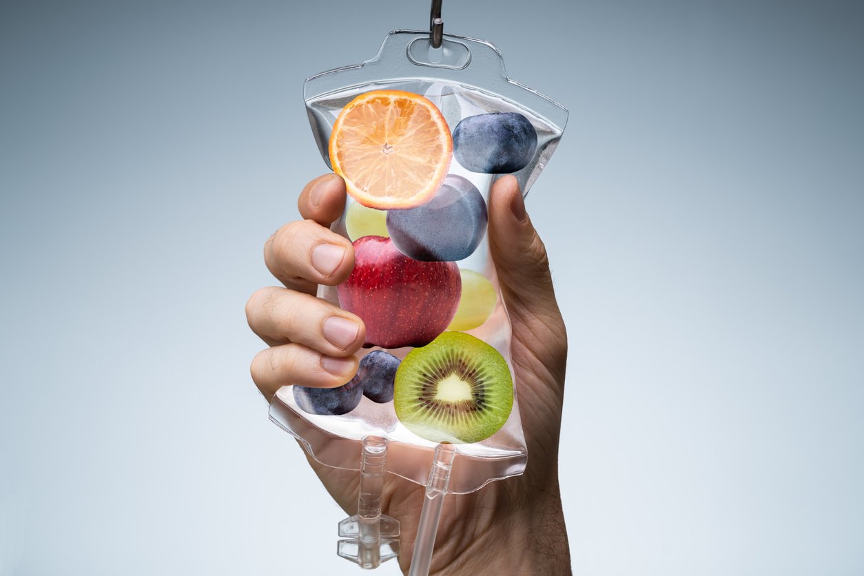 Human Hand Holding Saline Bag With Fruit Slices Over Grey Background